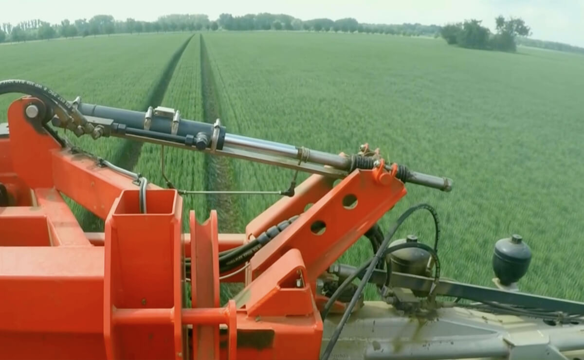 Blick von einer landwirtschaftlichen Sprühmaschine auf ein grünes Feld mit präzisen Fahrspuren