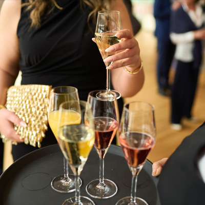 Gäste beim Sektempfang mit gefüllten Gläsern auf einem Tablett.