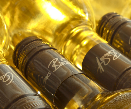 Goldgelbe Weinflaschen liegen nebeneinander. Auf den Schraubverschlüssen steht Claus Bischoff.