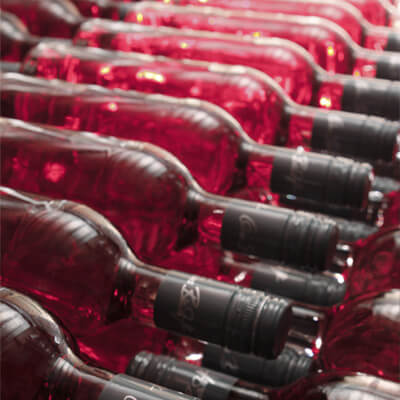 Reihenweise liegende Rotweinflaschen mit schwarzem Schraubverschluss